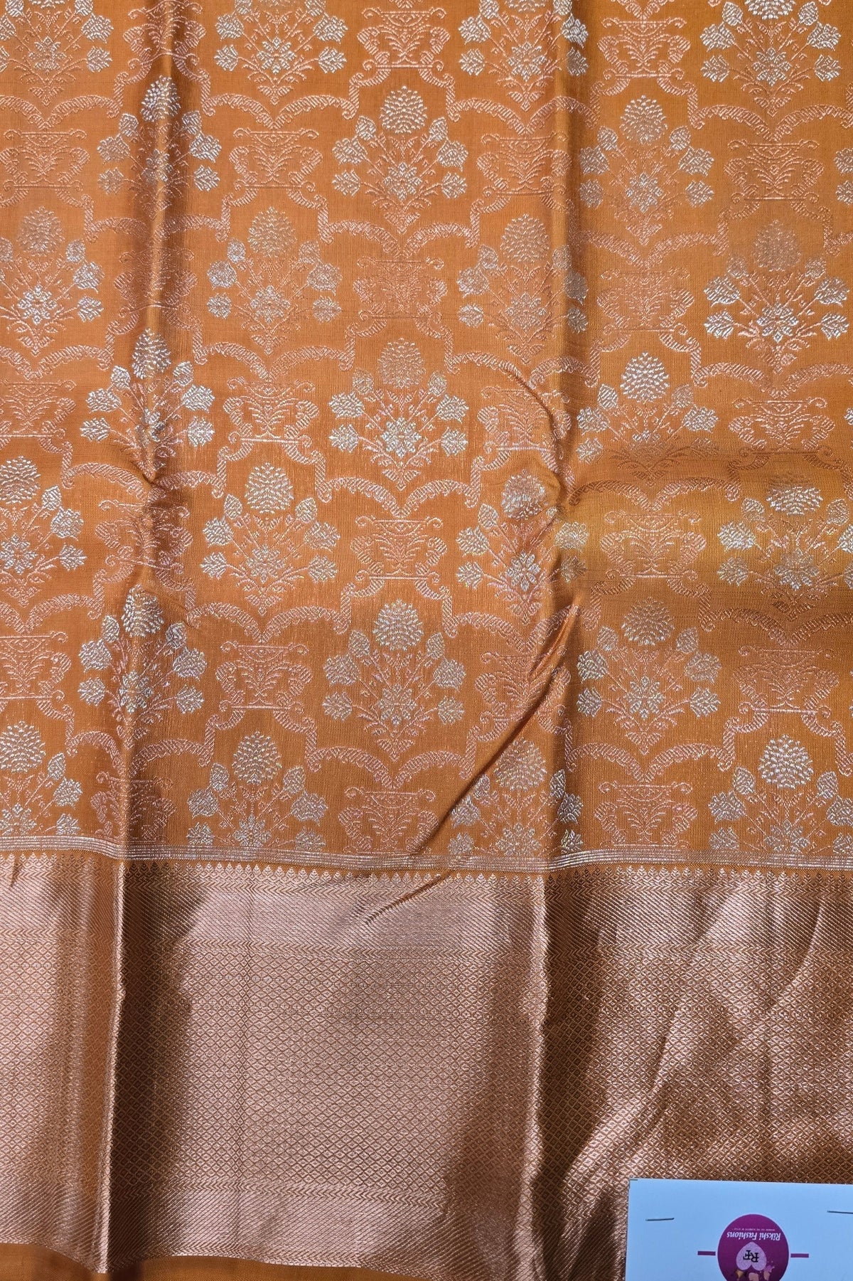 Brown fabric with floral patterns and a visible brand label in the corner.