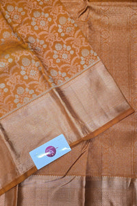 Brown saree with floral patterns and a visible brand label.