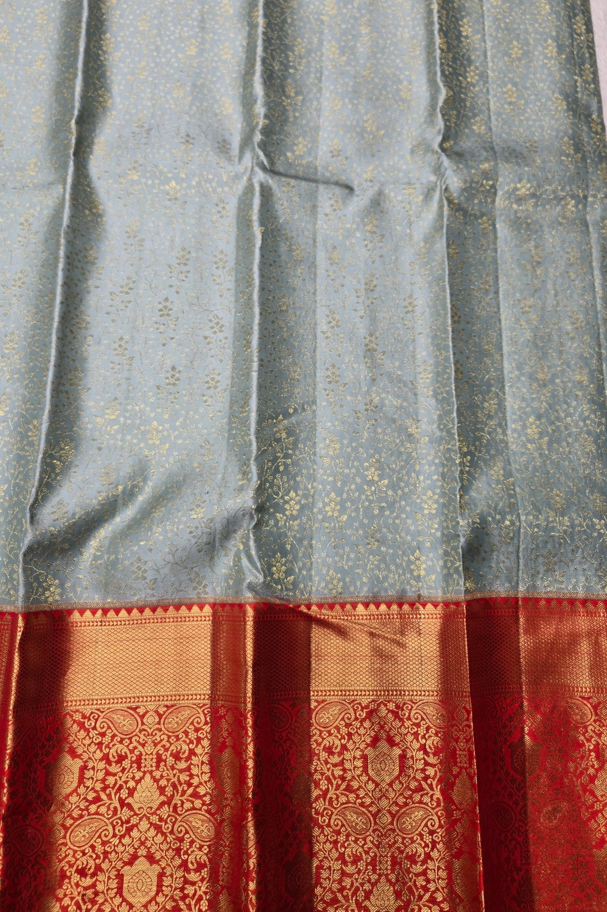 Silk saree with a patterned border in red and gold on a gray background