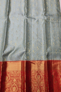 Silk saree with a patterned border in red and gold on a gray background