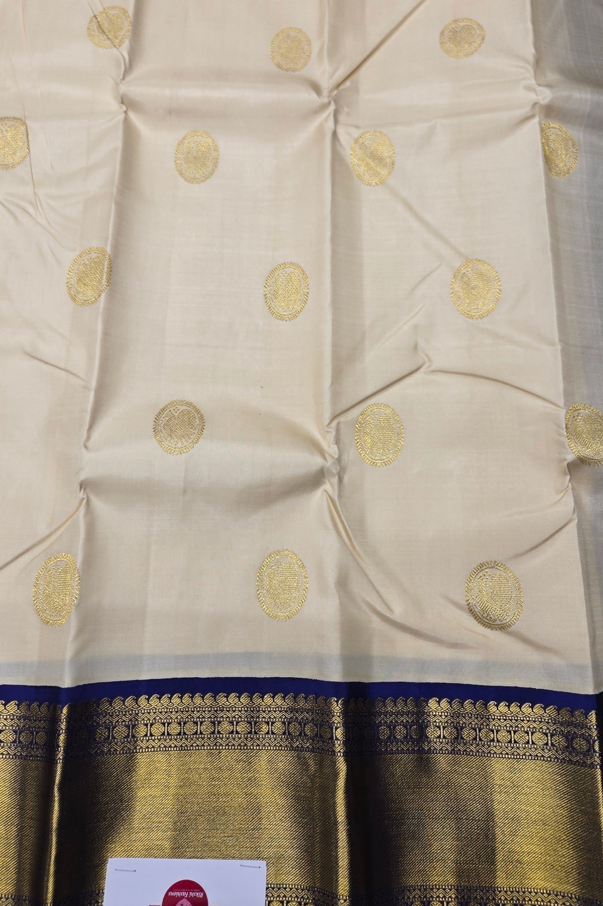 Beige fabric with gold circular patterns and a blue border