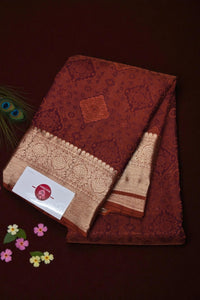 Brown saree with lace border on a dark background