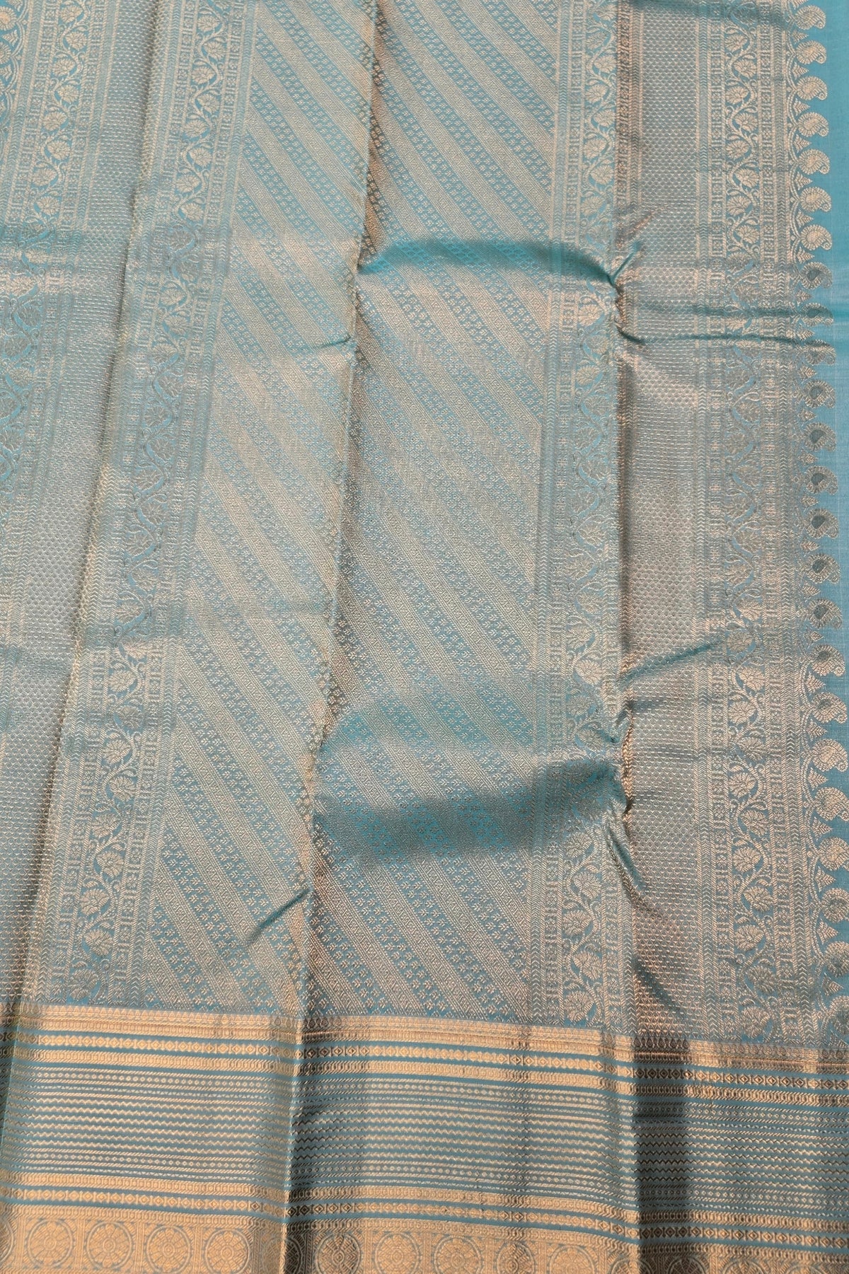Close-up of a light blue fabric with intricate patterns and a border.
