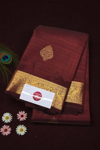 Maroon saree with gold border and a card on a dark background