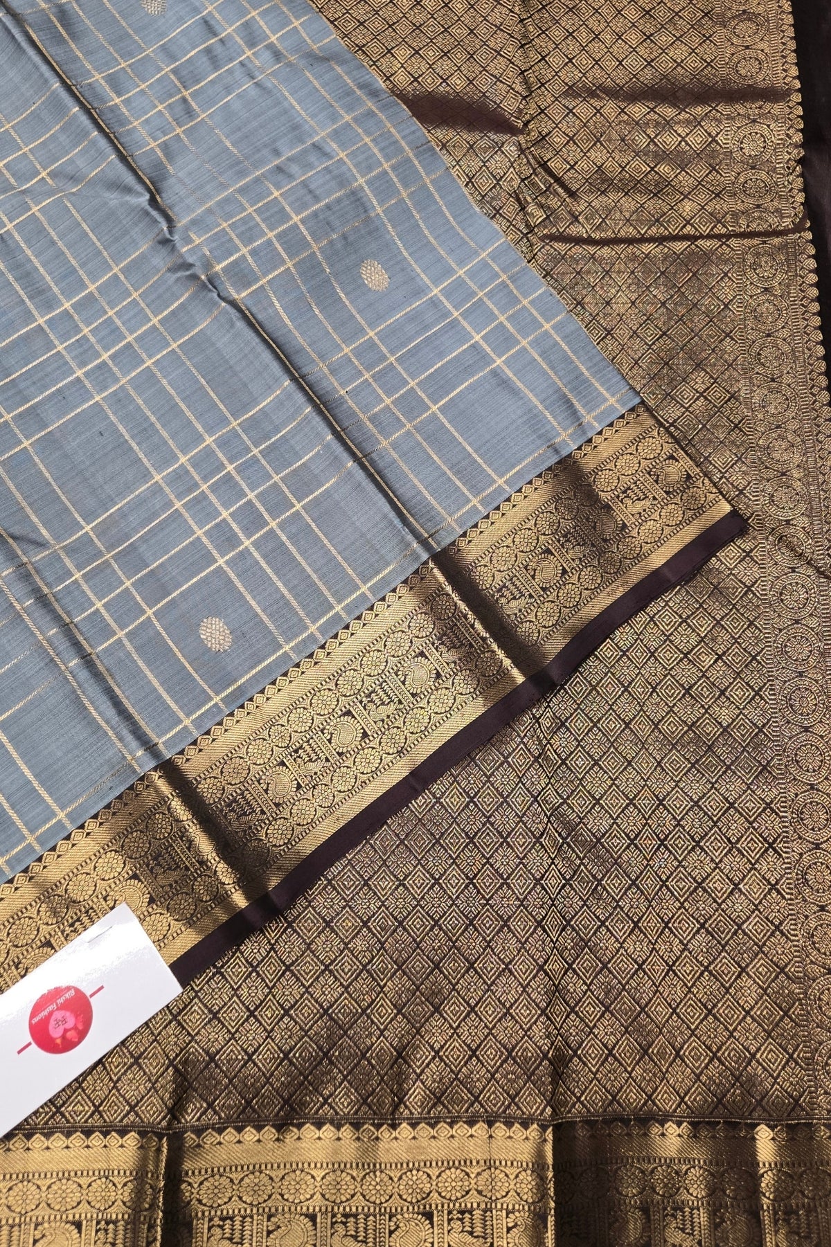 Close-up of a saree with a blue and gold border, featuring a brand label.