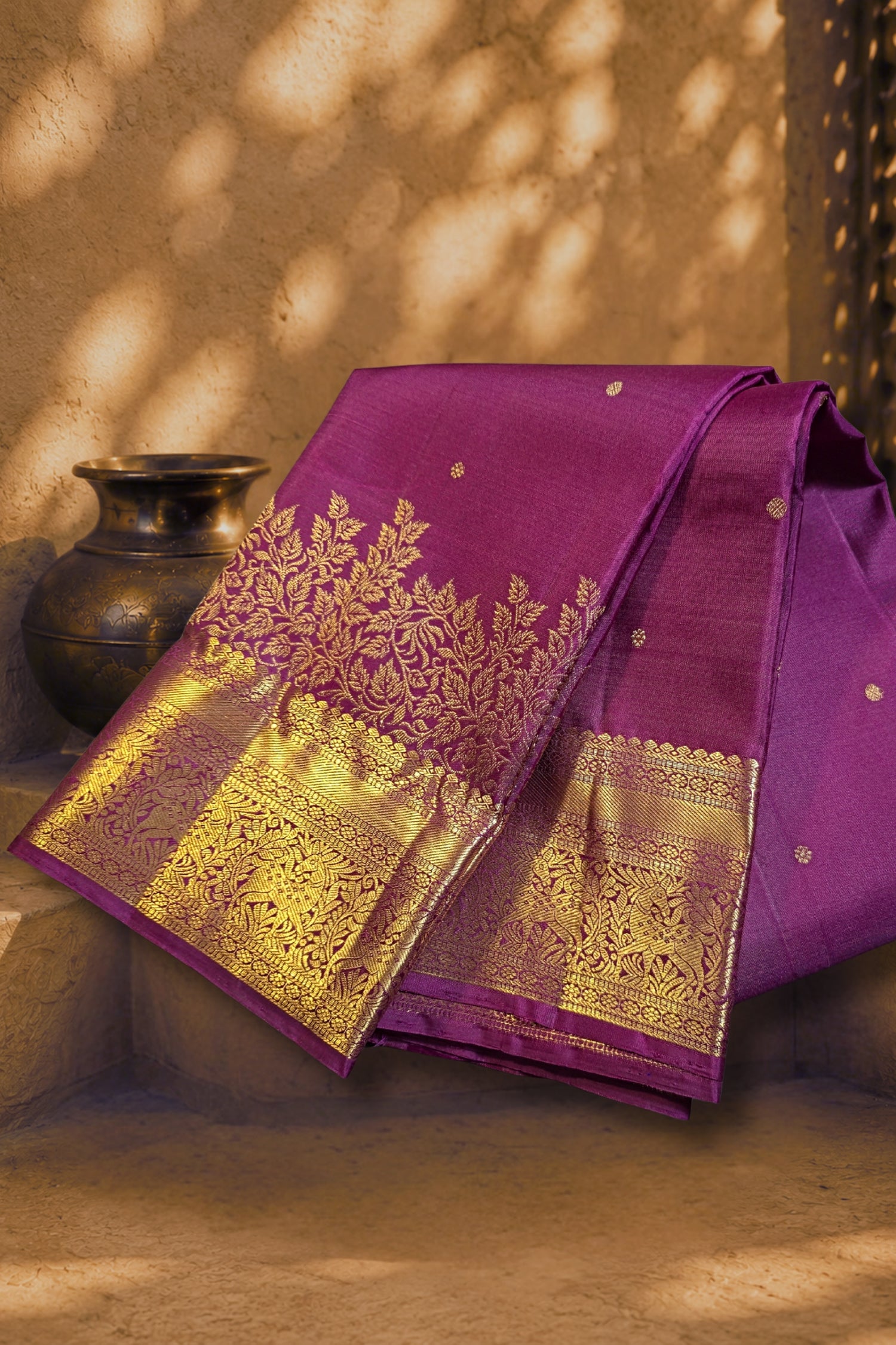 Purple silk saree with gold zari embroidery folded elegantly, showcasing intricate designs and rich colors.