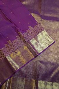 Purple silk saree with intricate gold zari brocade work and a wide decorative border, shown in a close-up diagonal layout.