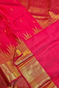 A close-up of a bright pink silk saree with a wide gold zari border and small gold motifs woven throughout.