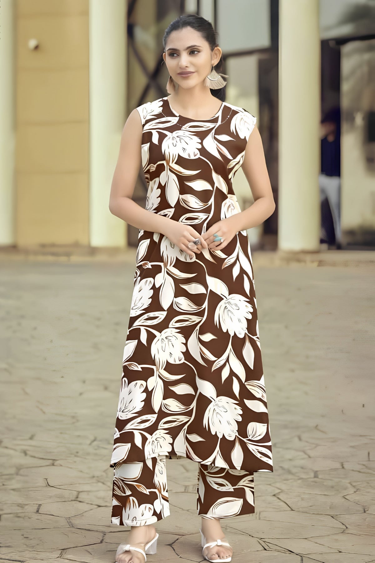 Woman wearing a brown floral dress standing on a paved area.
