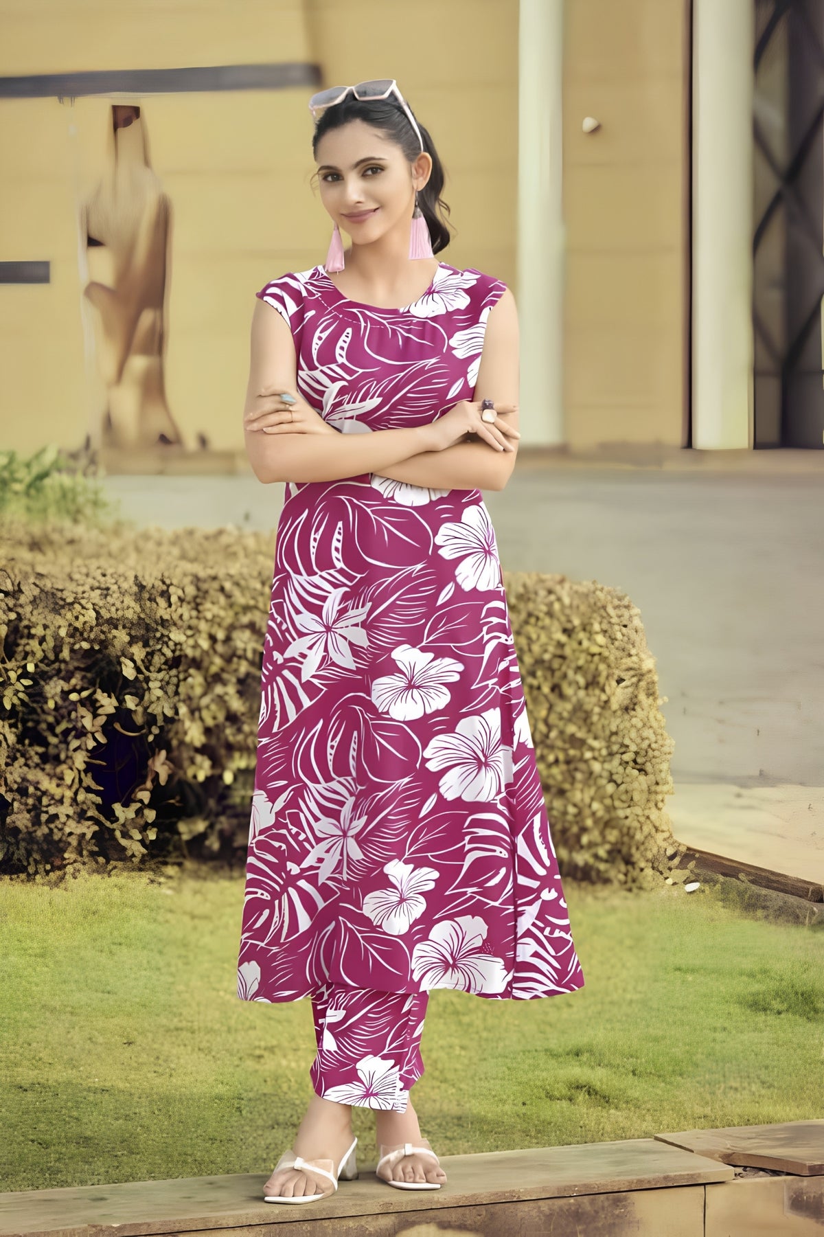 Woman wearing a pink floral dress standing outdoors on a grassy area.
