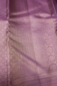 A close-up of a lavender purple woven fabric with metallic gold zari patterns and borders.