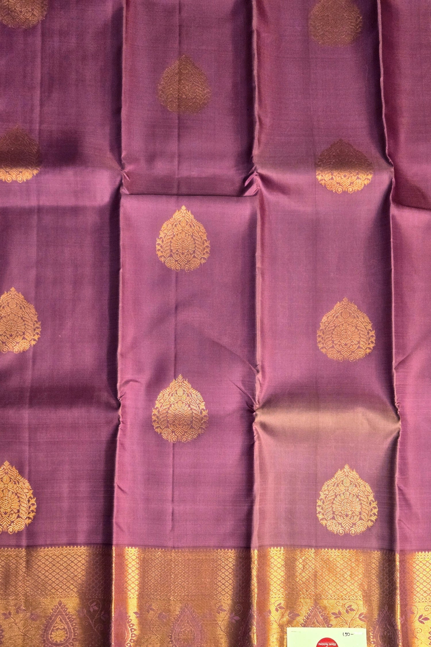 Close-up of intricate gold zari weaving on purple silk fabric