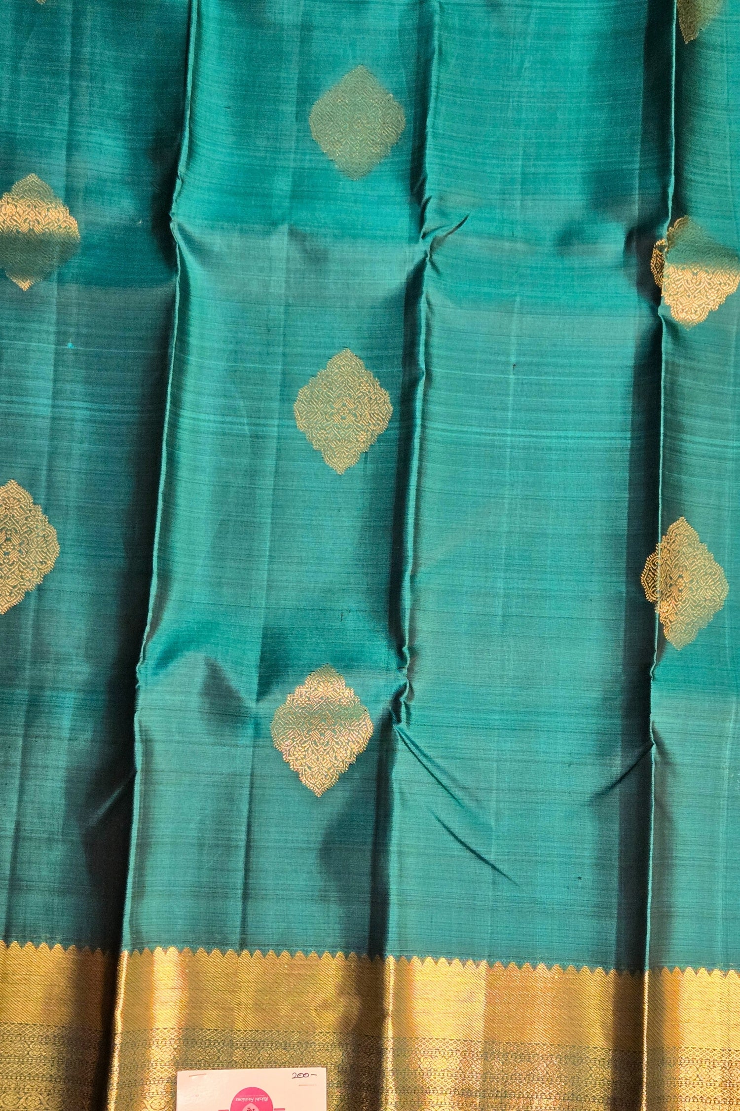 Close-up of traditional zari motifs on teal blue silk fabric