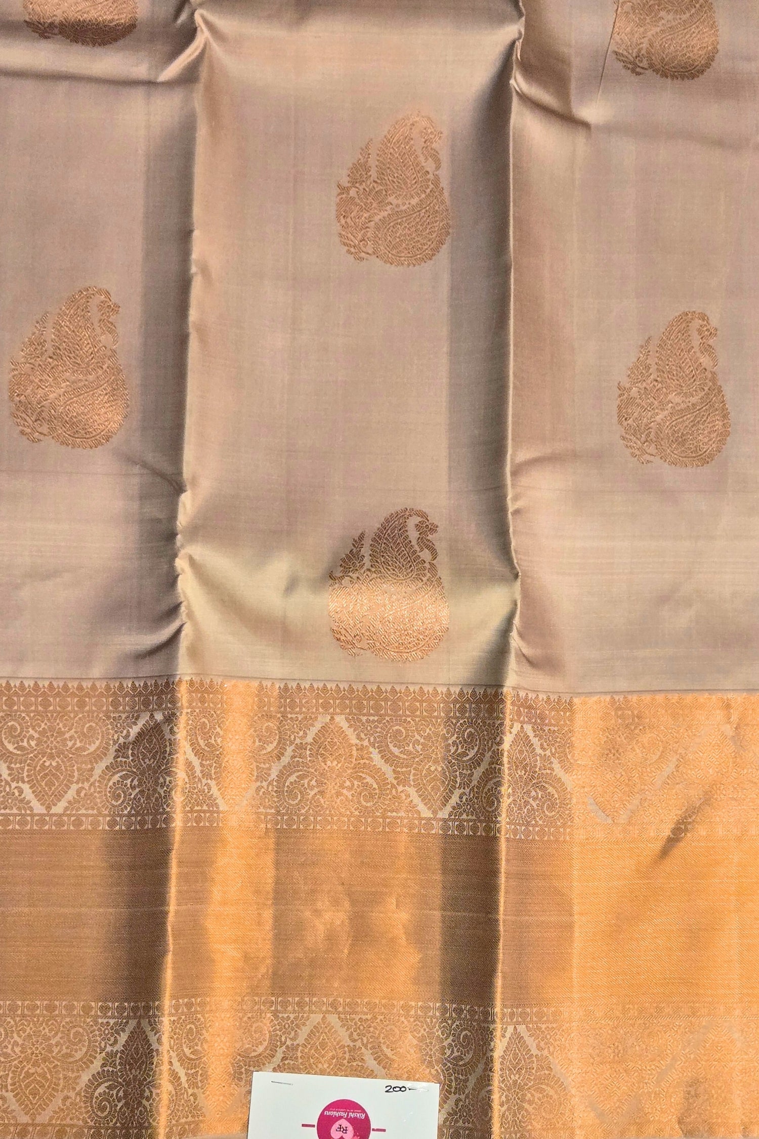 Close-up of woven zari motifs on rosy brown silk fabric