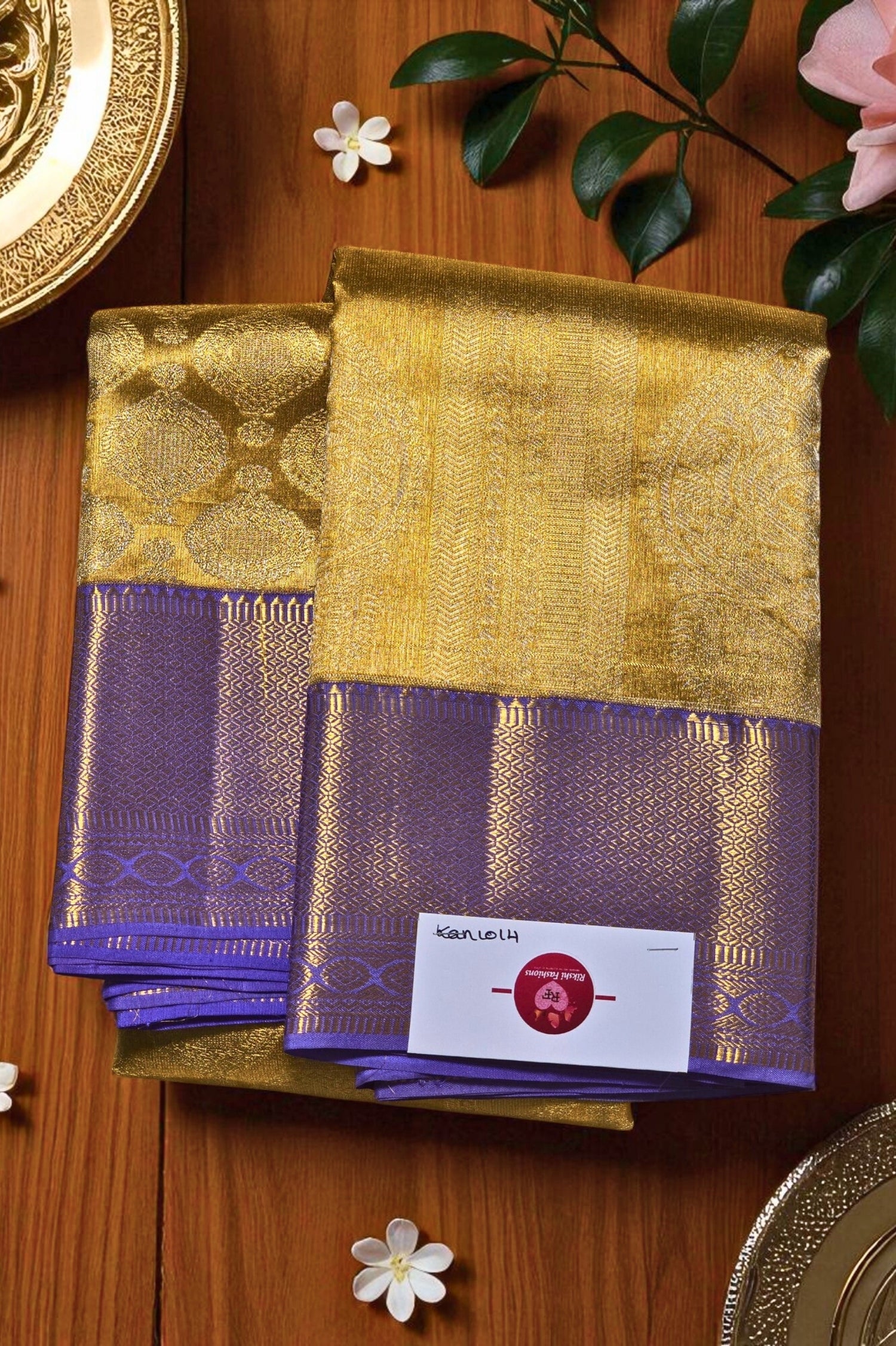 Gold and purple fabric with a brand label on a wooden surface with flowers.