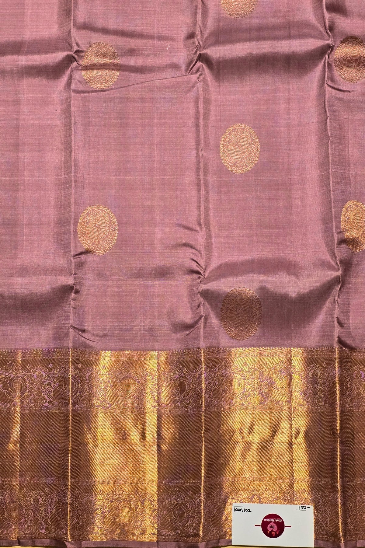 Pink saree with gold patterns and a brand label in the corner