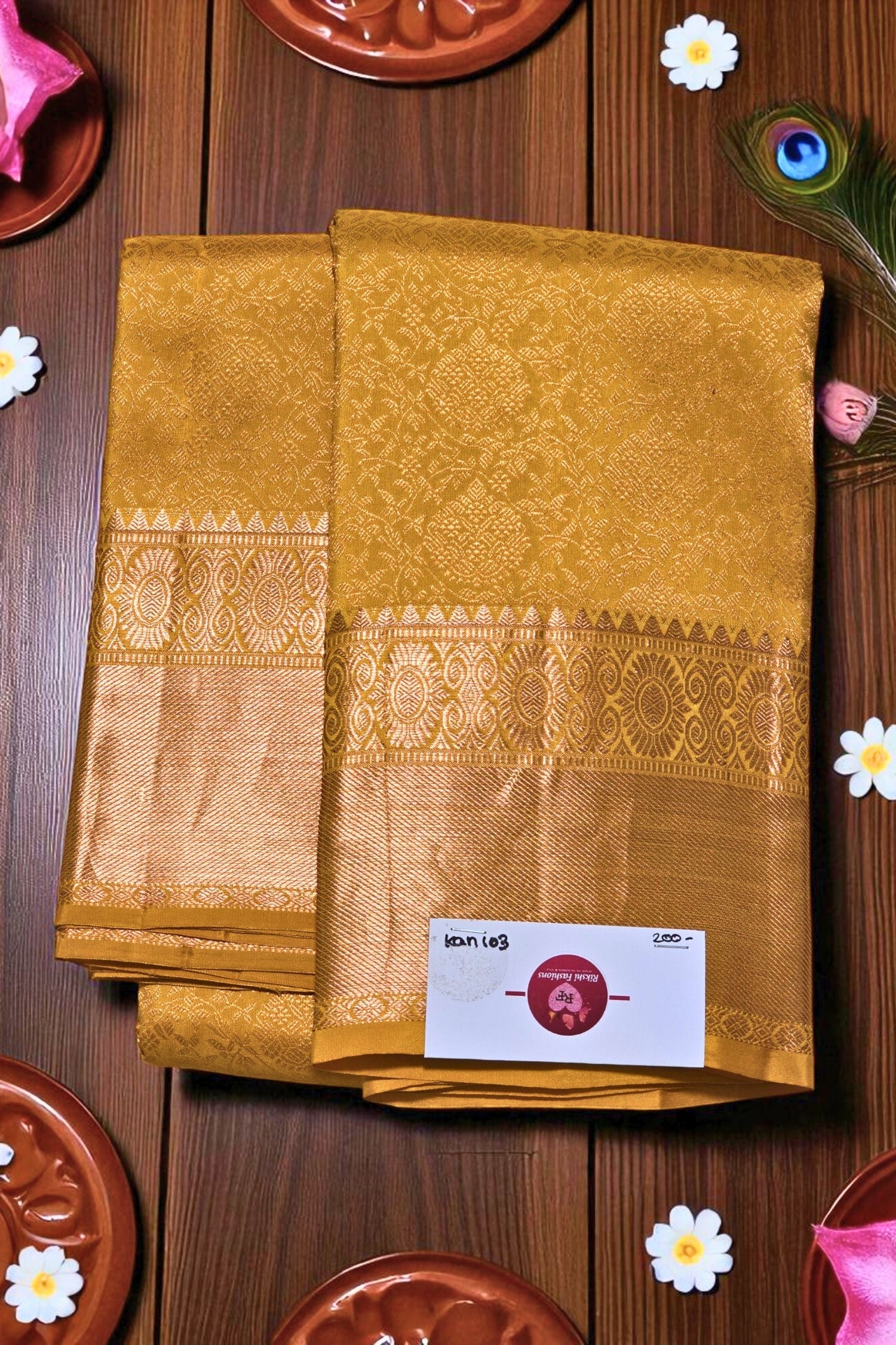 Mustard yellow saree with a border on a wooden surface with decorative elements.