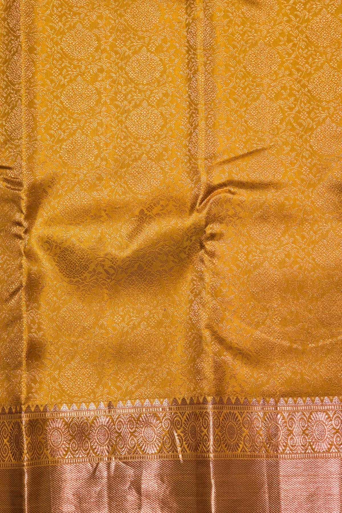 Gold-colored fabric with intricate patterns and a border