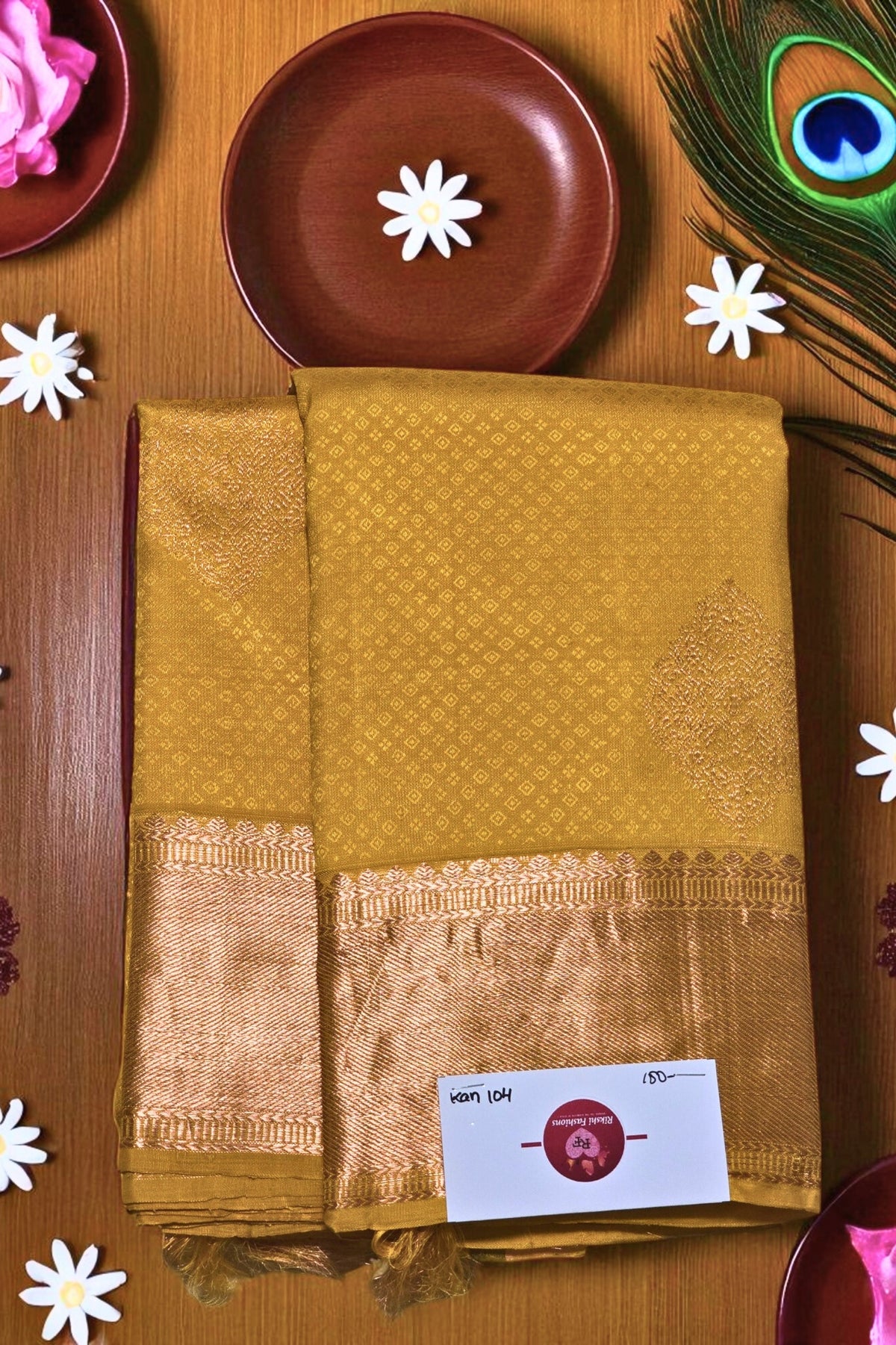 Mustard yellow saree with a border on a wooden surface with decorative elements.