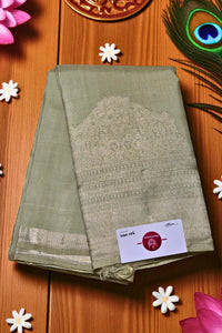 Green saree with silver border on a wooden surface with decorative elements