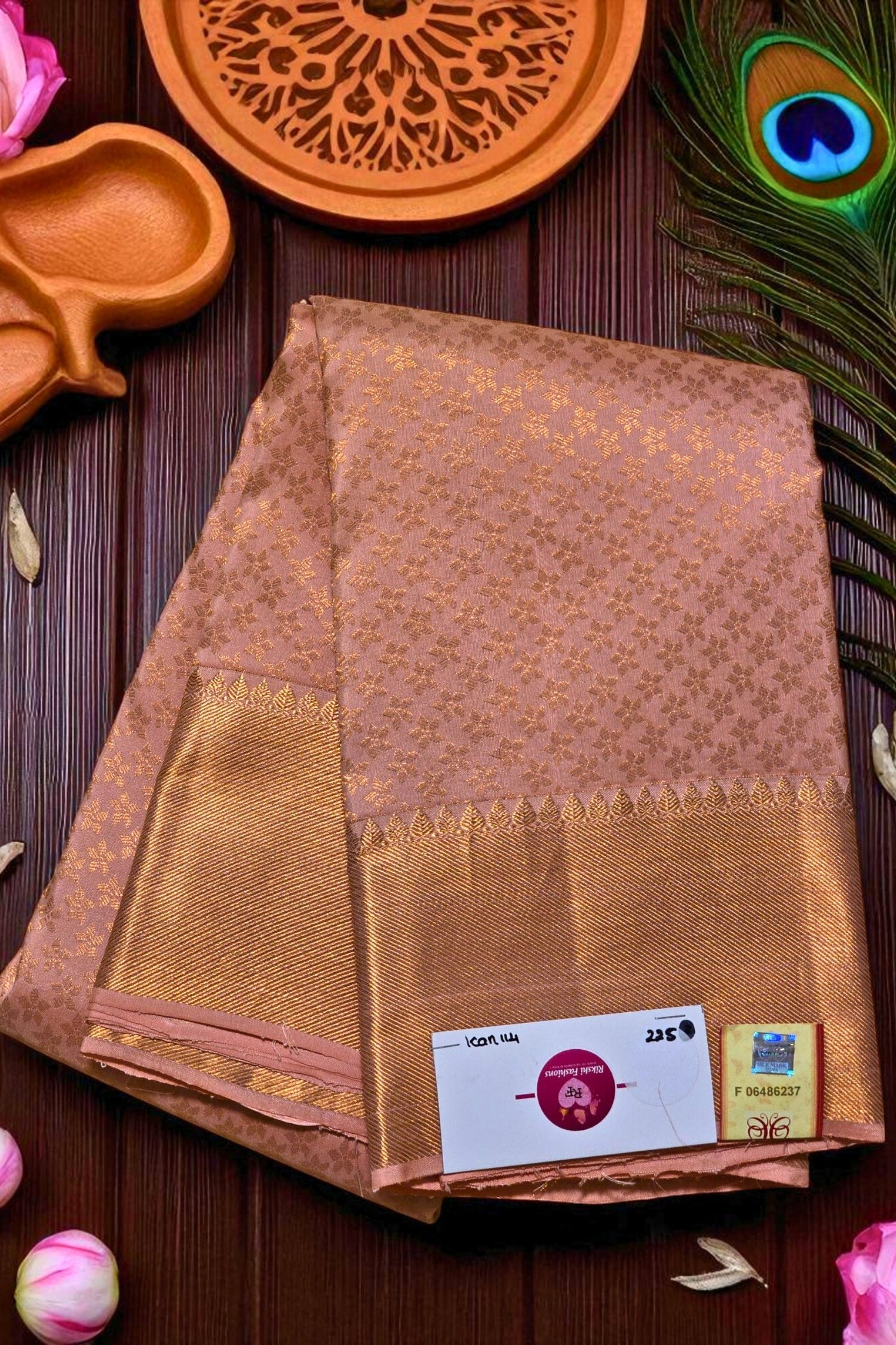 Brown saree with gold border on a wooden surface with decorative items.