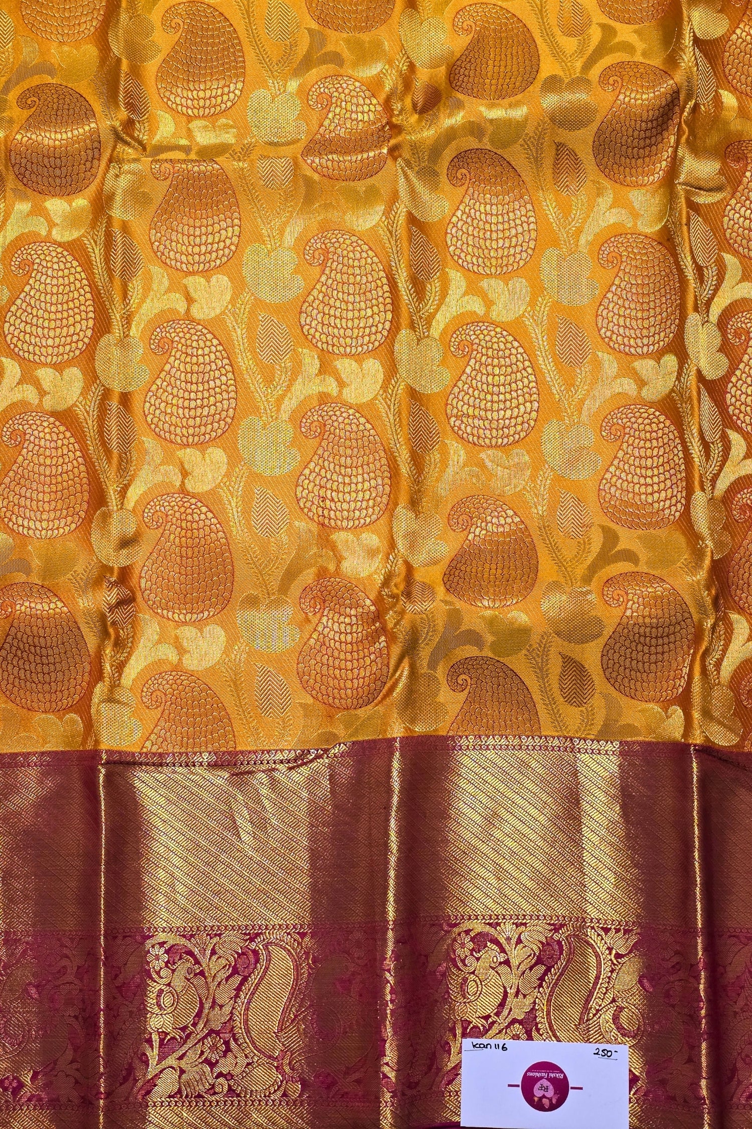 Gold and red fabric with intricate patterns and a visible brand label.