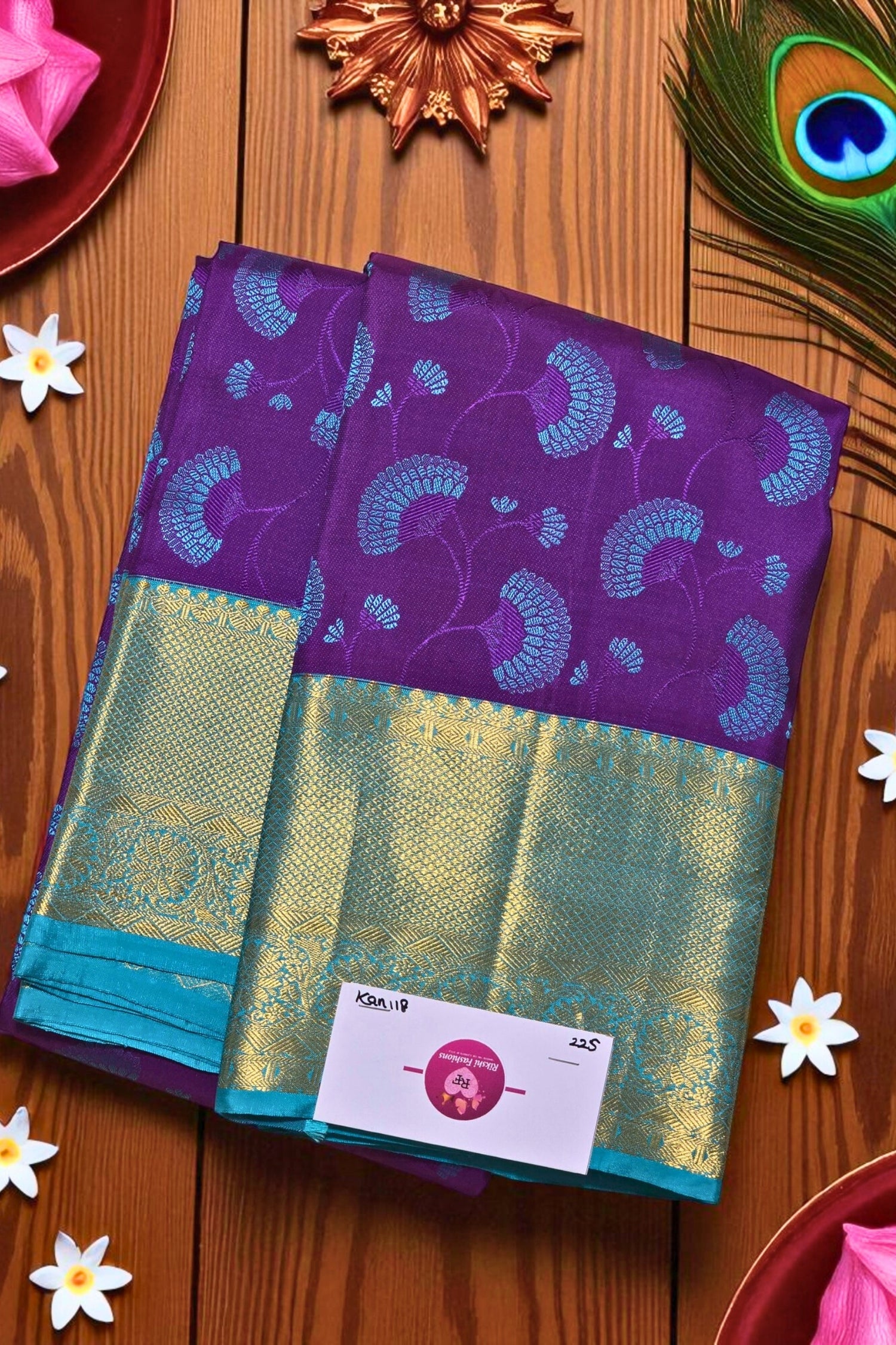 Purple and green saree with a brand label on a wooden surface with decorative elements.