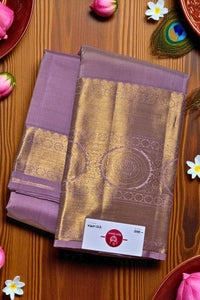 Purple and gold saree with a brand label on a wooden surface with decorative elements.