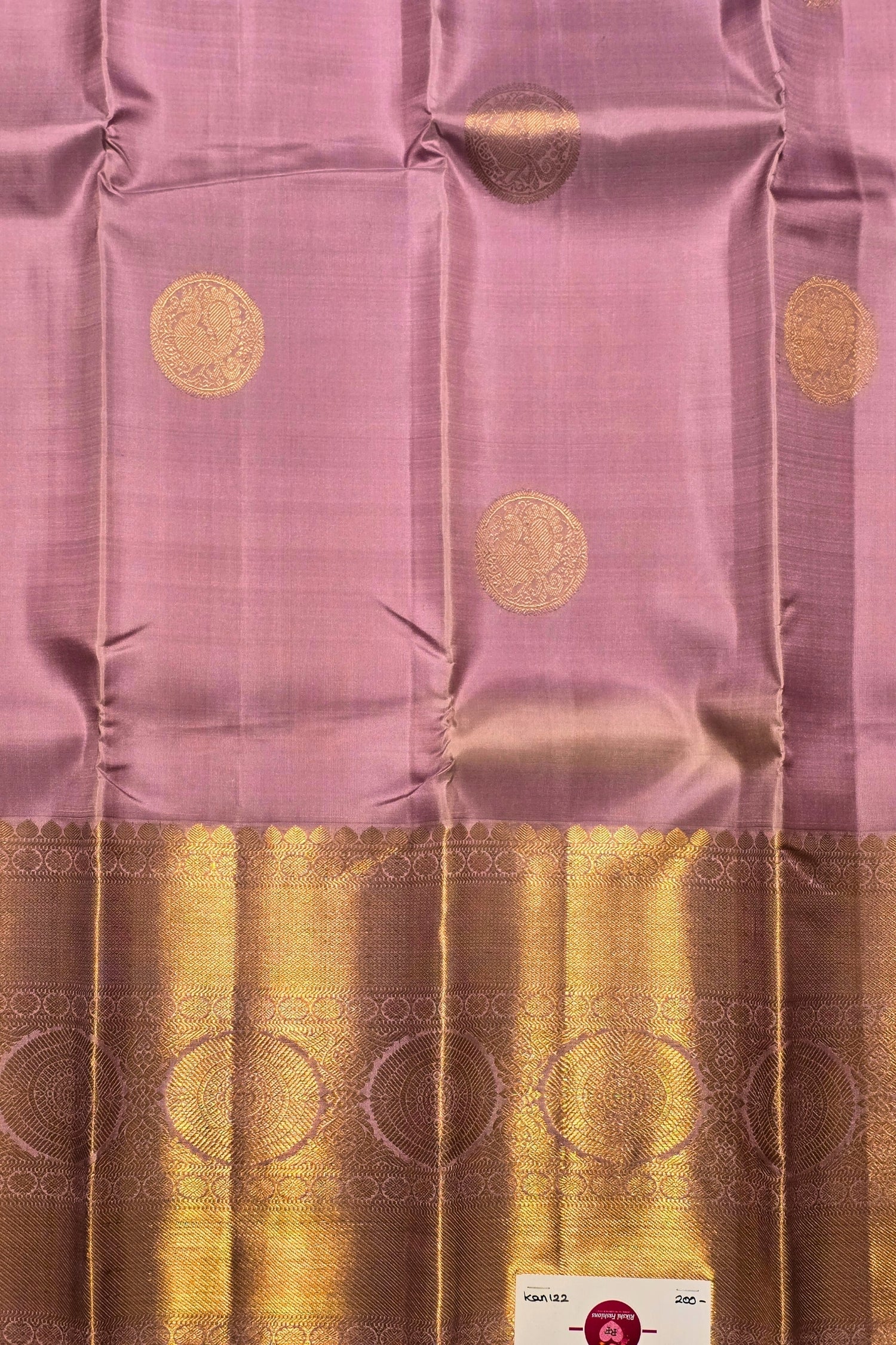 Pink fabric with gold patterns and a brand label in the corner
