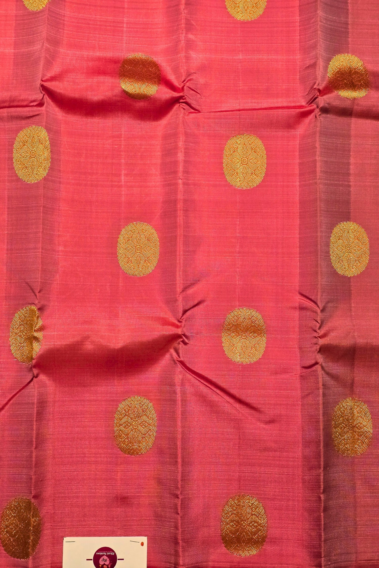 Red fabric with gold polka dots and a visible brand label.