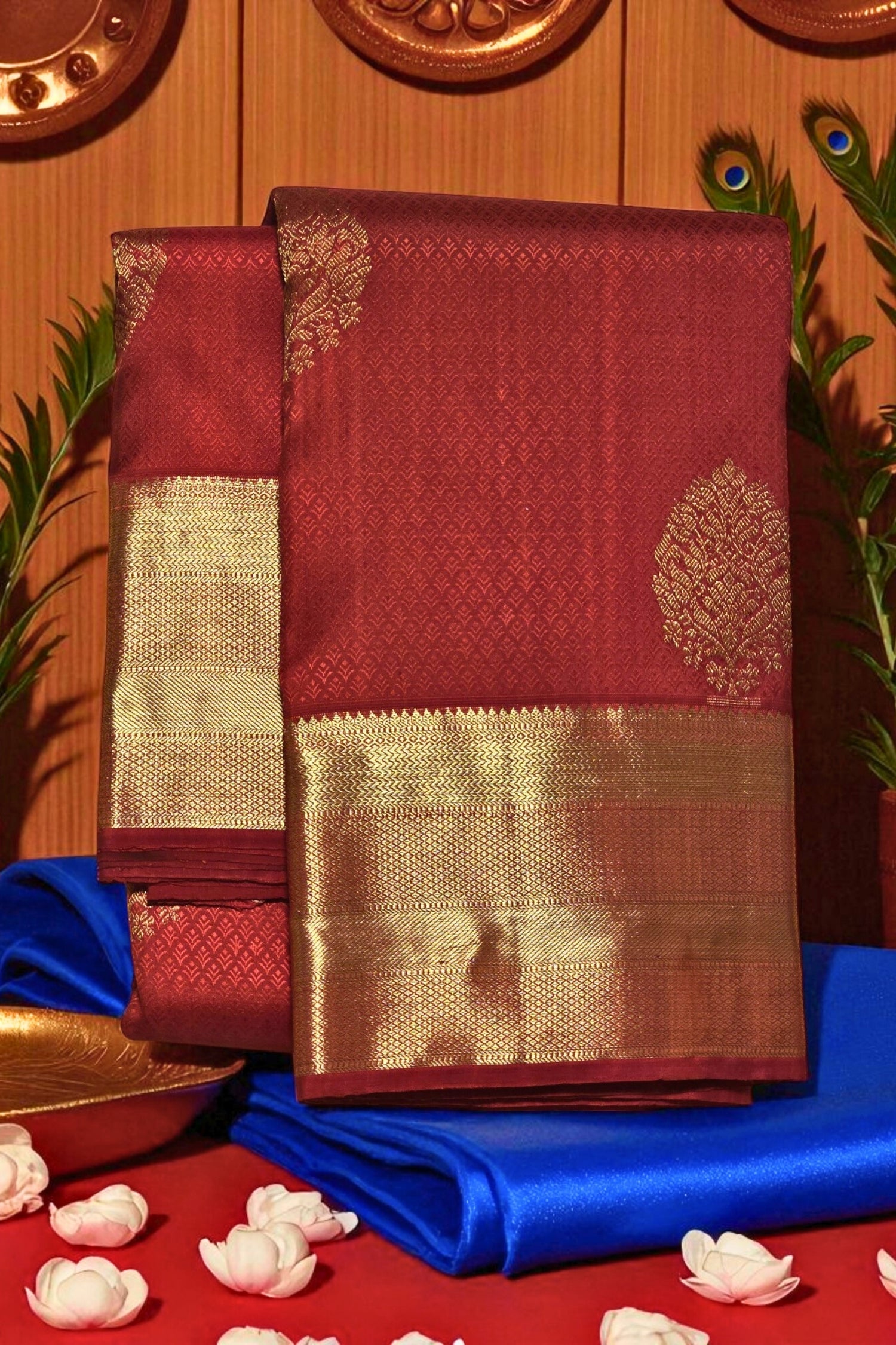 Maroon saree with gold border on a blue and red fabric background