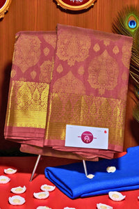 Two pink sarees with gold patterns on a stand against a wooden background.