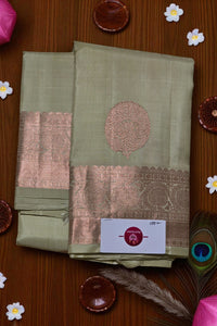 Green saree with pink border on a wooden surface with decorative items