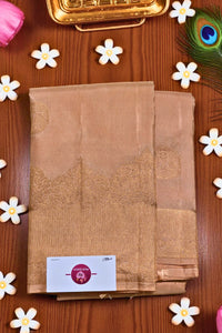 Brown saree with a brand label on a wooden surface with decorative flowers and a peacock feather.