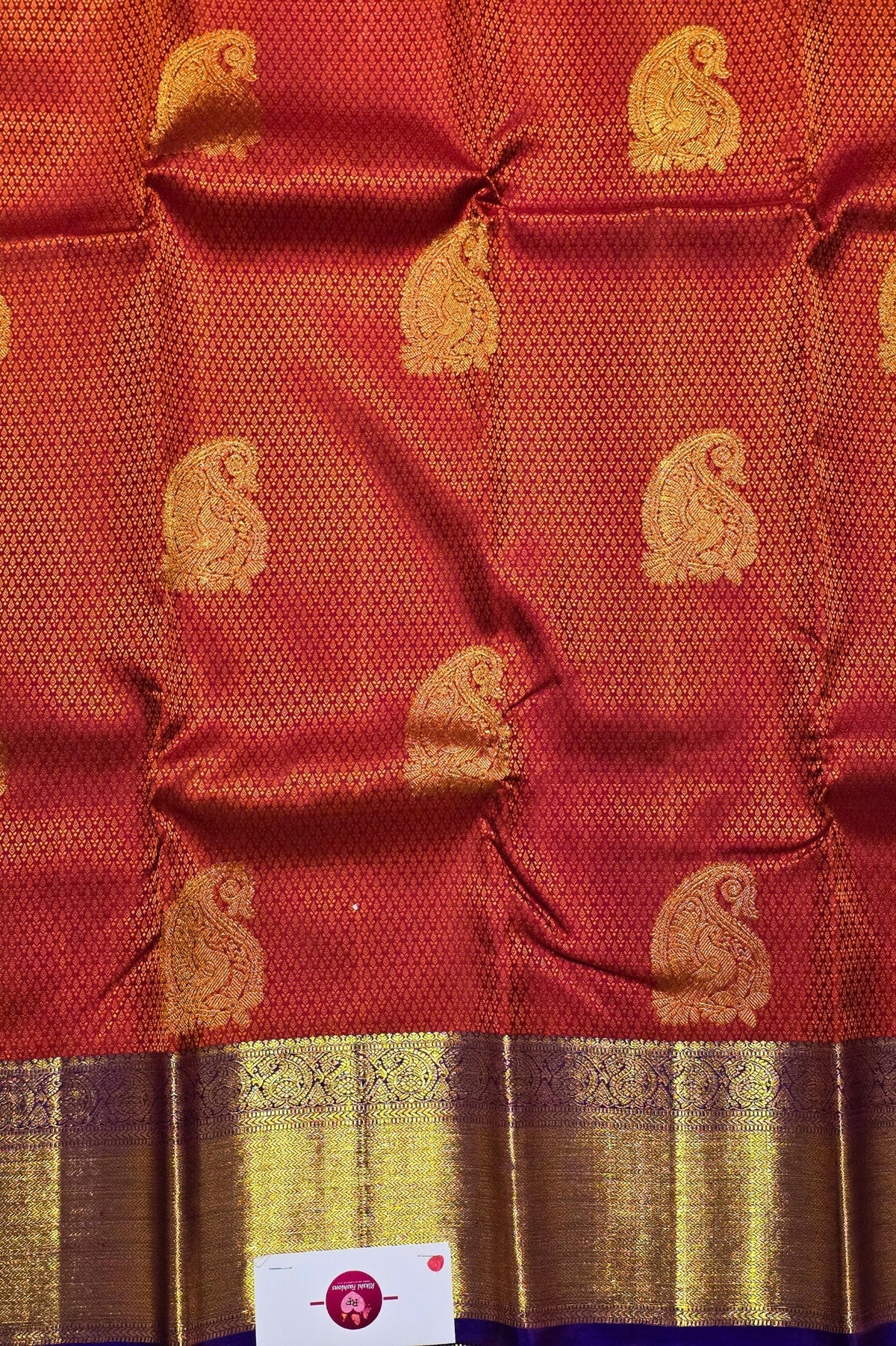 Red fabric with gold patterns and a visible brand label.