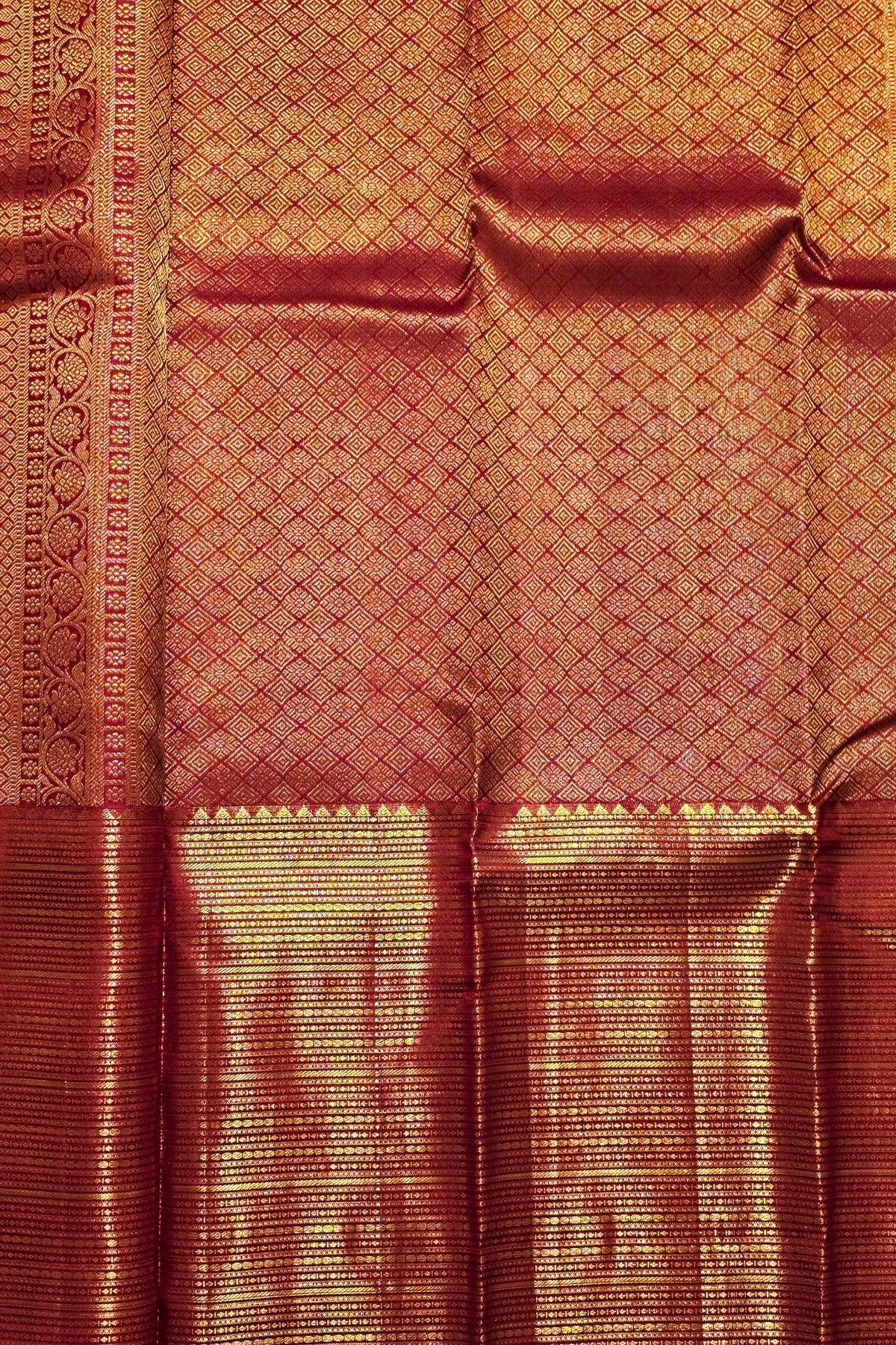 Close-up of a maroon fabric with gold border and intricate patterns