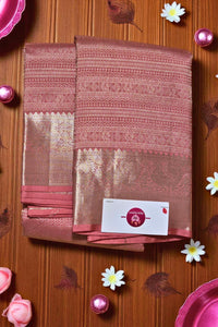 Folded saree with a brand label on a wooden surface with decorative elements