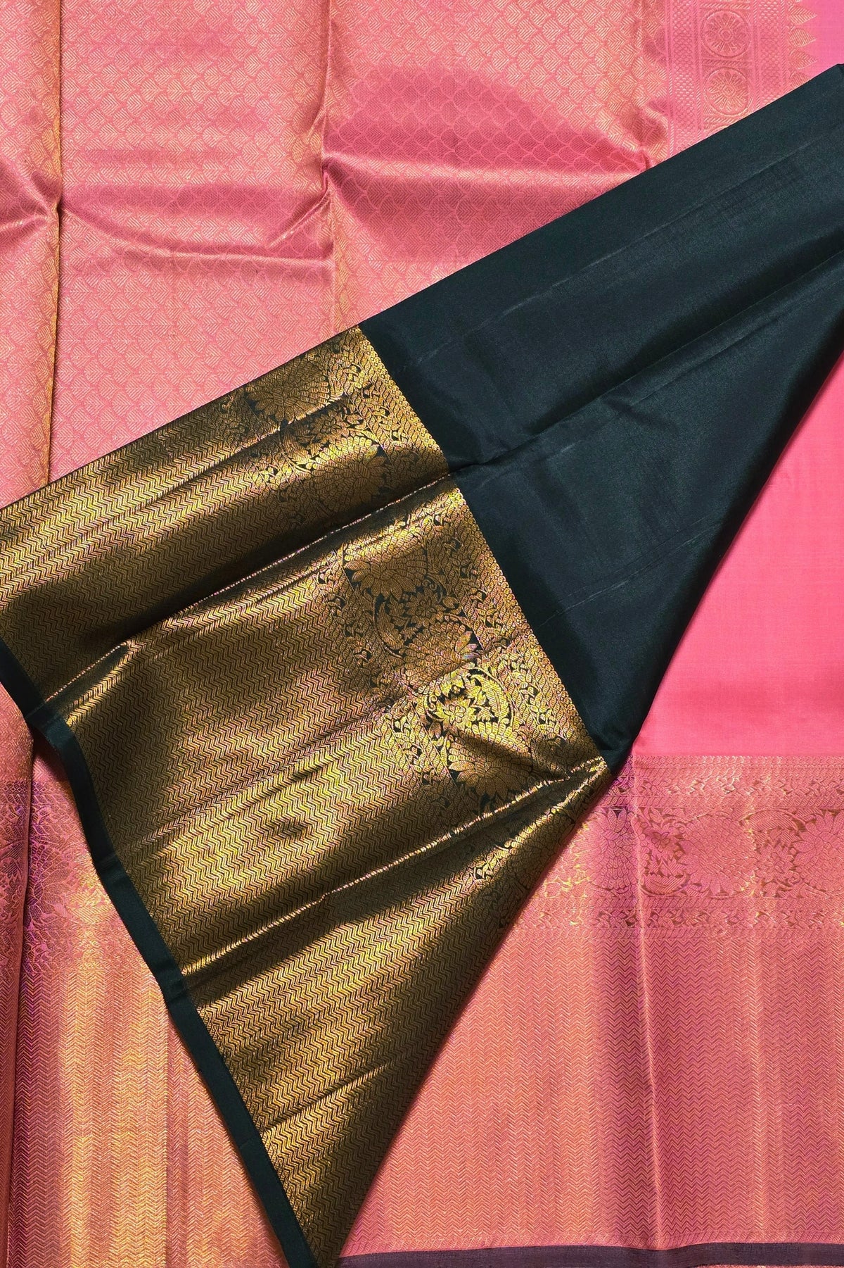 Close-up of a saree with gold and black border on a pink background