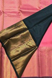 Close-up of a saree with gold and black border on a pink background