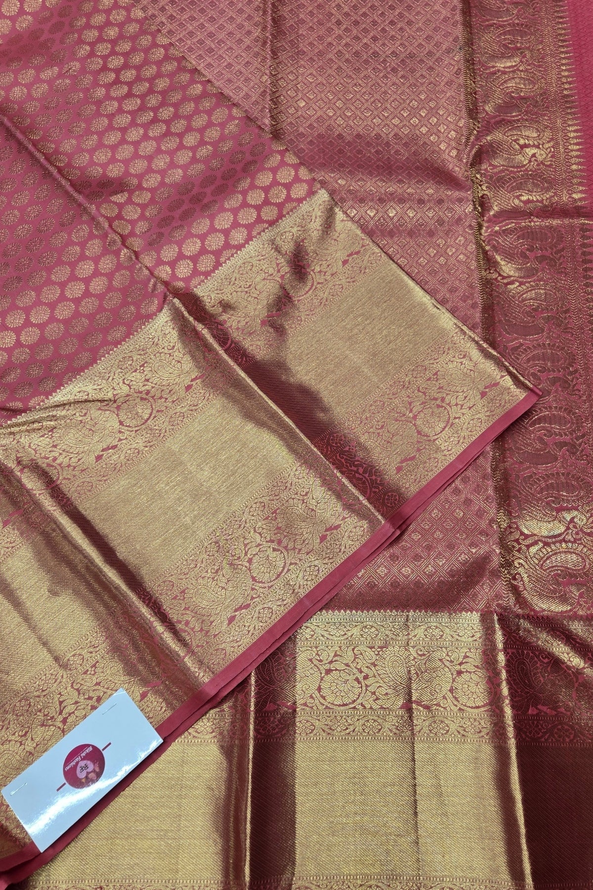 Maroon and gold saree with intricate patterns and a visible brand label.