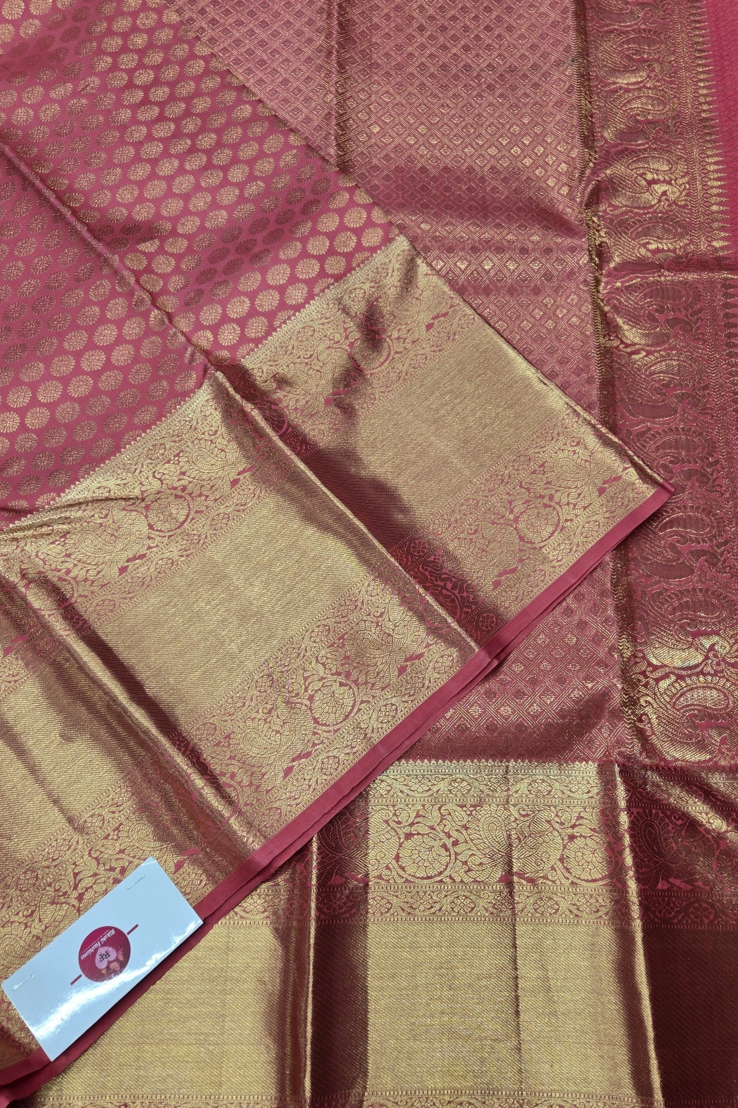 Maroon and gold saree with intricate patterns and a visible brand label.