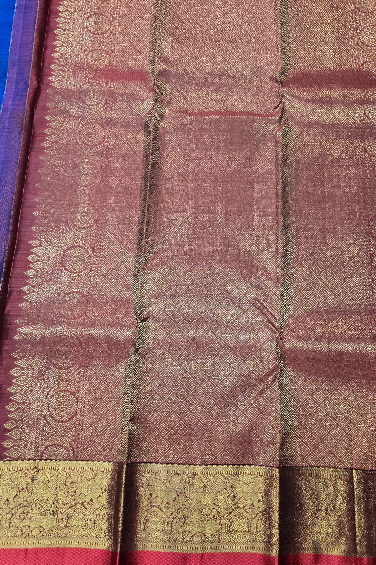 Close-up of a maroon saree with gold border and patterns