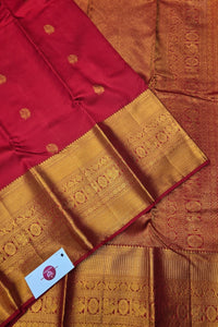 Red and gold saree with intricate patterns and a visible brand tag.