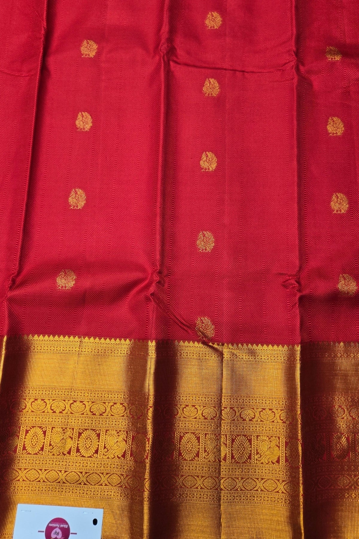 Red fabric with gold patterns and a visible brand logo in the corner.
