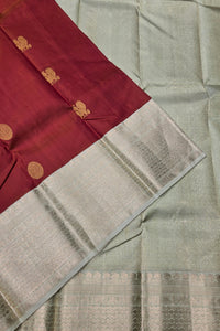 Saree with maroon border and gold embroidery on a light gray background