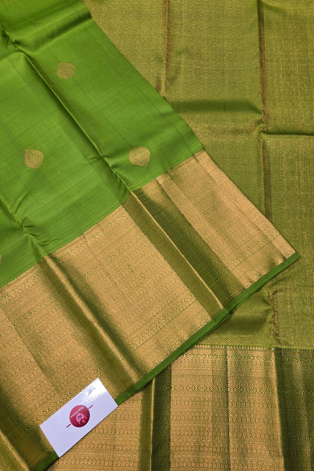 Green and gold traditional fabric with a brand label.