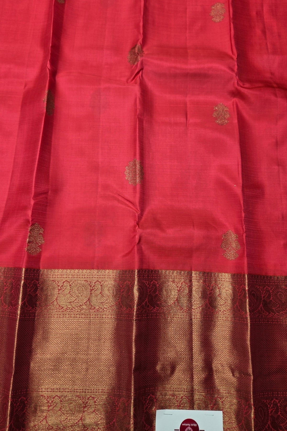 Red fabric with gold patterns and a visible brand label.