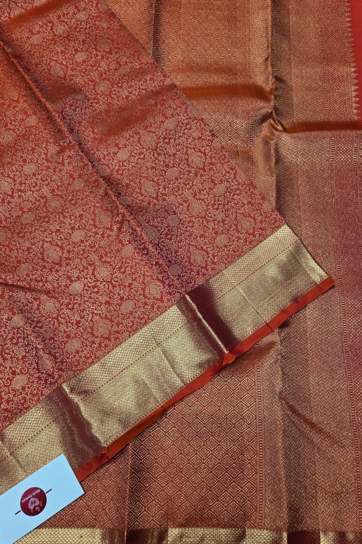 Close-up of a brown and gold saree with a visible brand label.