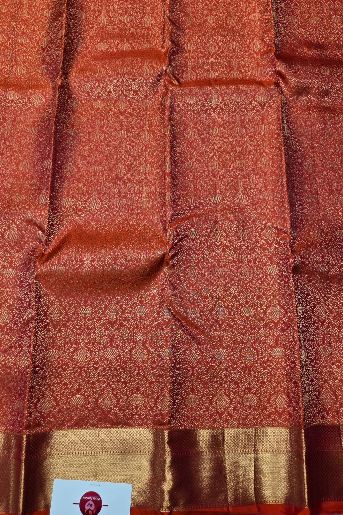 Red and gold patterned fabric with a visible brand label.