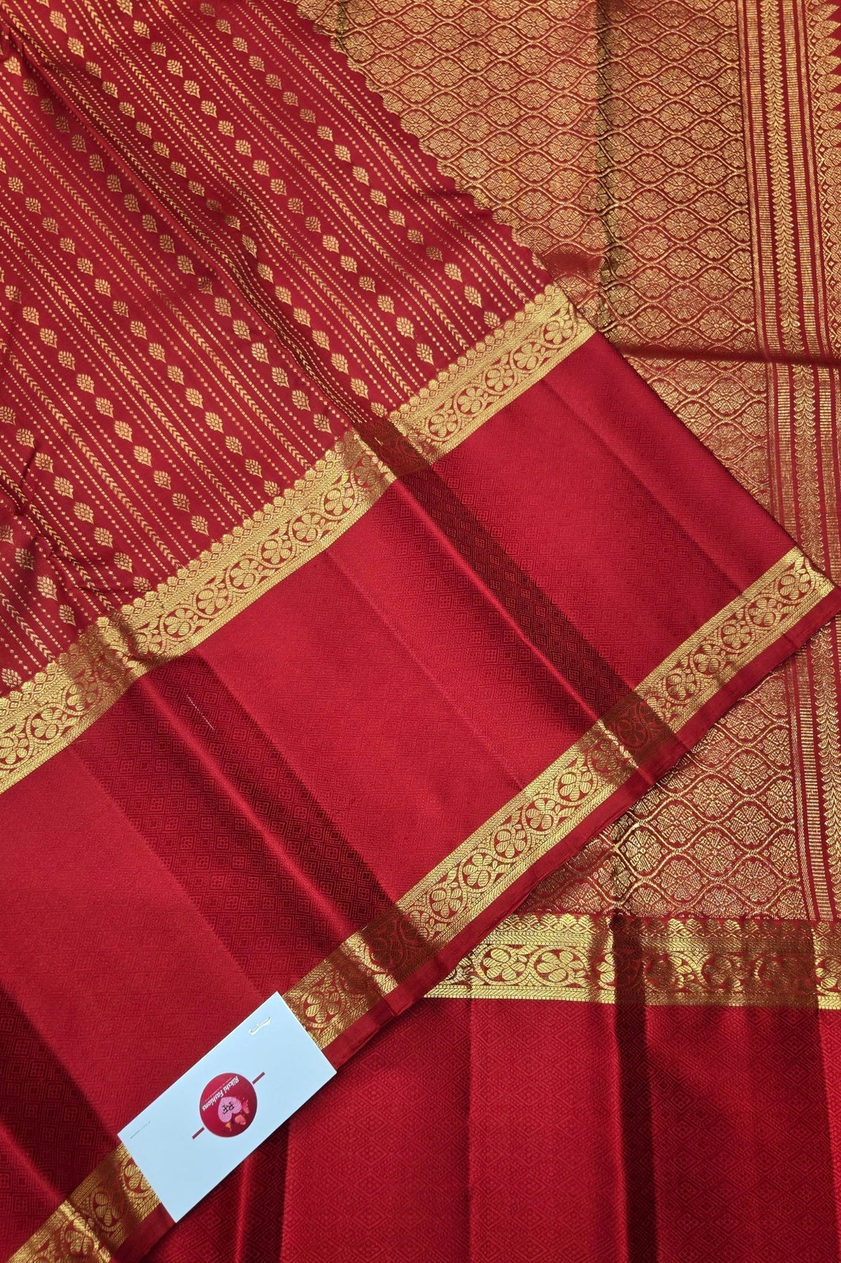 Red fabric with gold border and pattern, featuring a brand logo at the bottom.